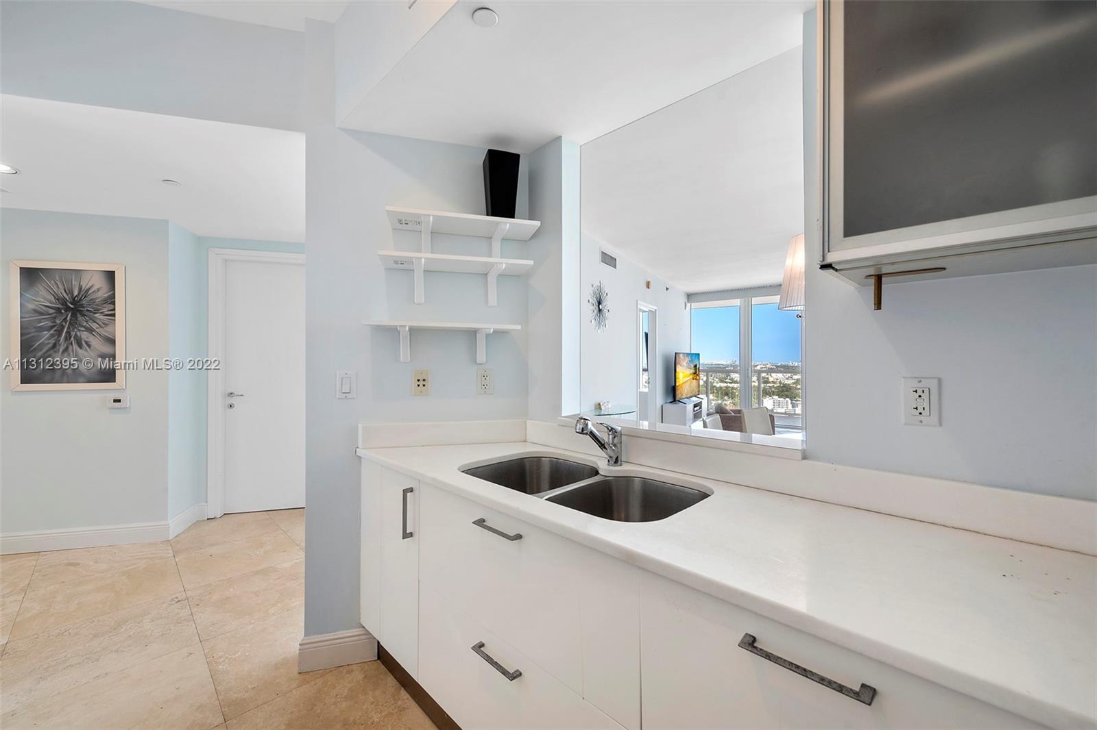450 Alton Road, Unit 3010 Miami Beach, FL 33139 - Photo 36 of 66 a kitchen with a sink a refrigerator and cabinets