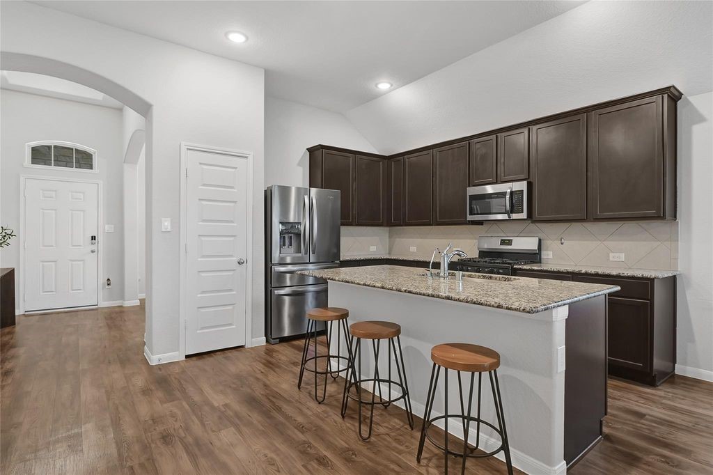 5422 Still Creek Ranch Drive Richmond, TX 77469 - Photo 8 of 28 a kitchen with stainless steel appliances granite countertop a refrigerator a stove top oven a sink dishwasher and wooden floor