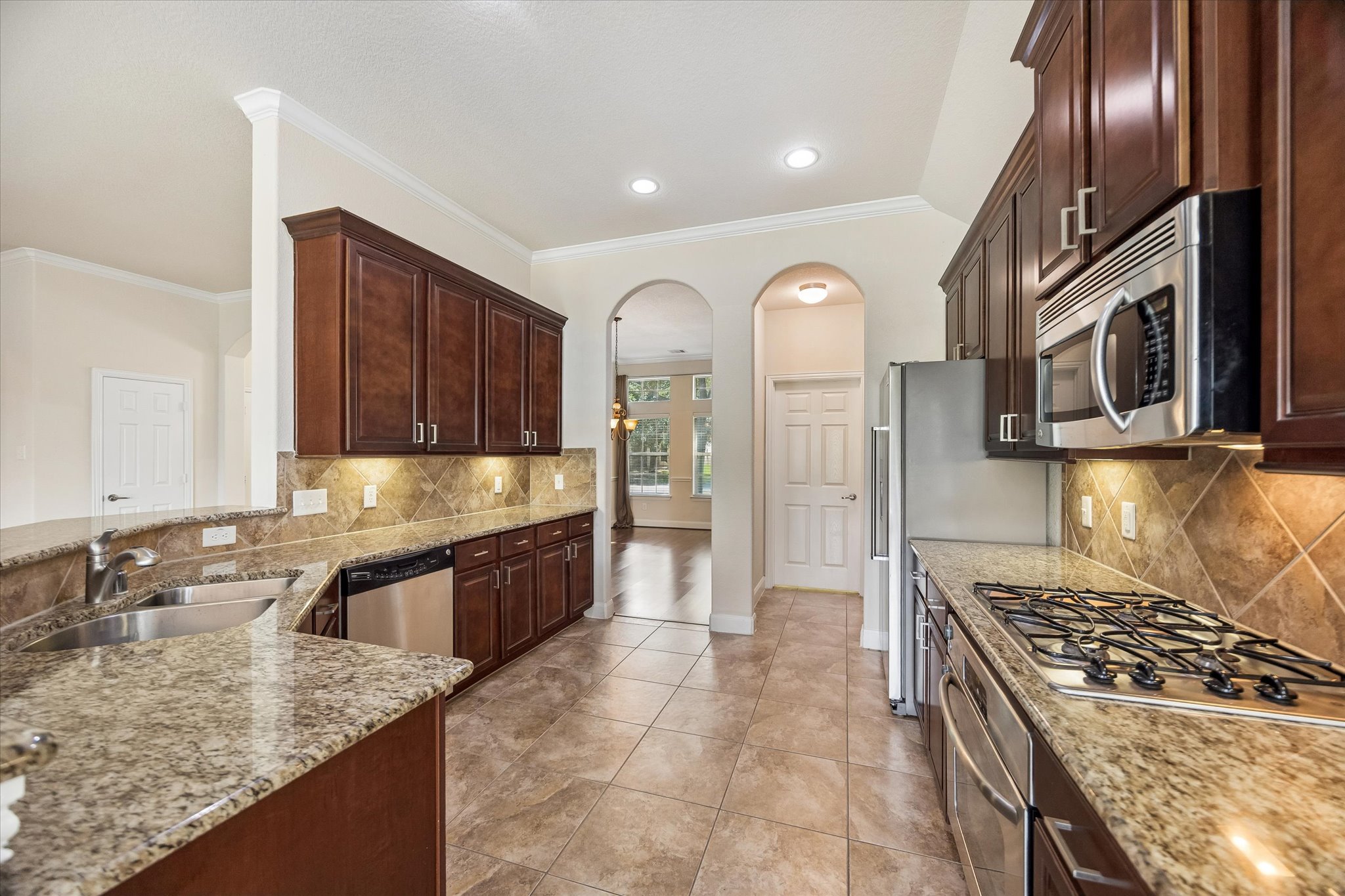 2214 Wembley Way Rosenberg, TX 77471 - Photo 22 of 35 Kitchen featuring rich wood cabinetry, stainless steel appliances, speckled countertops, and a tiled backsplash