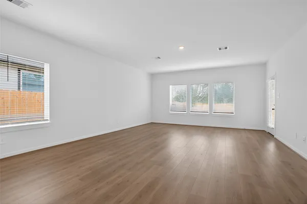 a kitchen with stainless steel appliances granite countertop a stove a sink a refrigerator and white cabinets with wooden floor