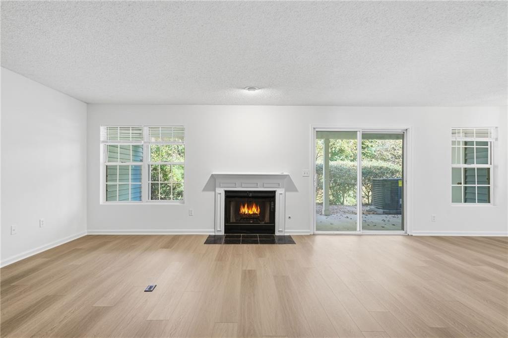 4053 Whitehall Way Alpharetta, GA 30004 - Photo 9 of 28 an empty room with a fireplace and windows