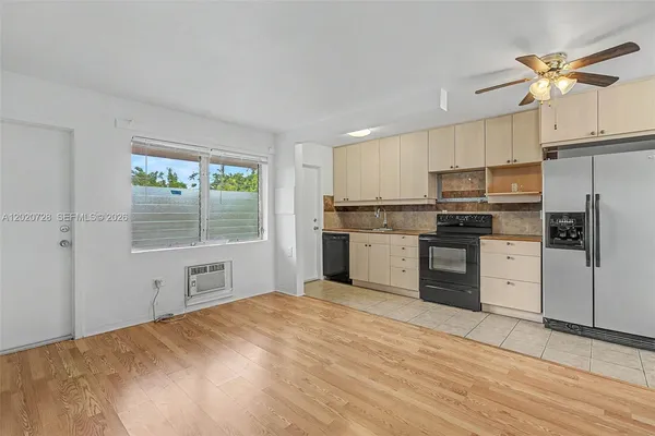 a kitchen with a refrigerator a stove top oven and white cabinets
