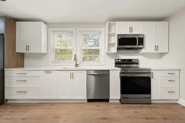 a kitchen with stainless steel appliances white cabinets and a stove top oven