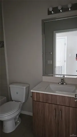 a bathroom with a granite countertop sink and a toilet