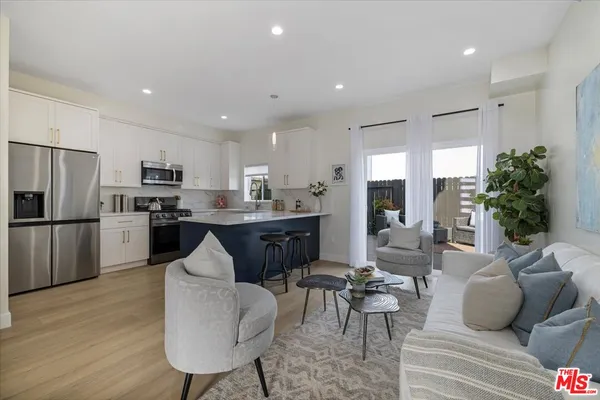 a living room with stainless steel appliances kitchen island granite countertop a couch and a refrigerator