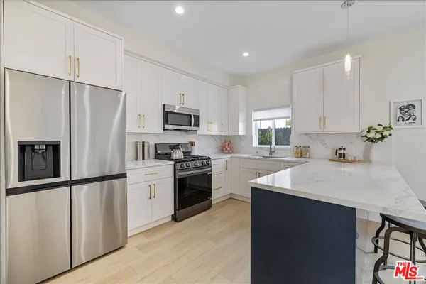 a kitchen with a refrigerator a stove top oven a sink and cabinets