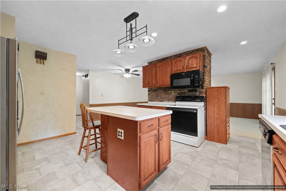 1835 Lynn Road Kent, OH 44240 - Photo 9 of 48 Kitchen featuring a central island with white countertop, wood-finish cabinetry, tile flooring, and a brick-finish backsplash