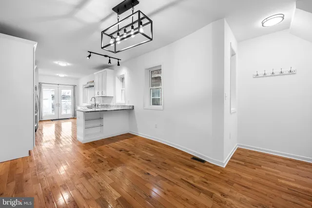 a view of kitchen and empty room with wooden floor