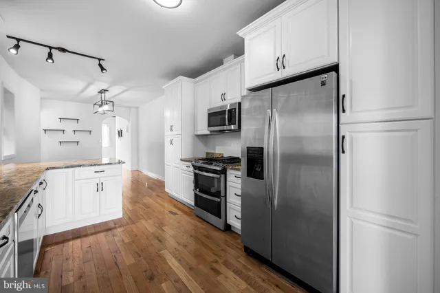 a large kitchen with a refrigerator a sink a stove and cabinets