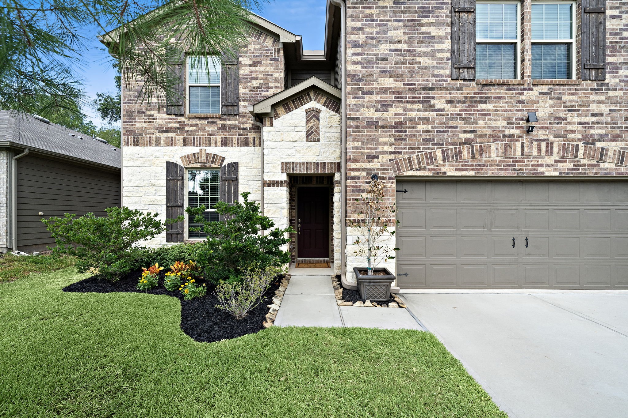 4210 Amber Ruse Drive Conroe, TX 77304 - Photo 2 of 45 The property includes a spacious driveway leading to a two-car garage, and the exterior has a welcoming entrance with rustic shutters.