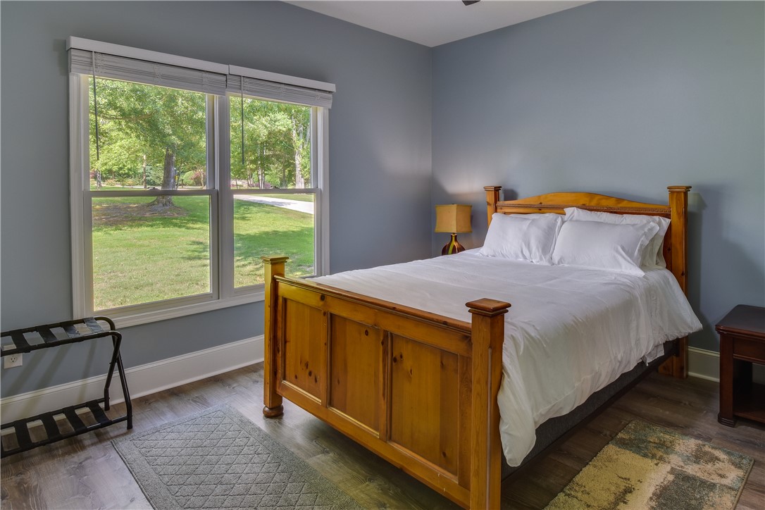 206 Petty Road Seneca, SC 29672 - Photo 19 of 48 A tranquil bedroom with wood flooring and a refreshing view of greenery through a large window.