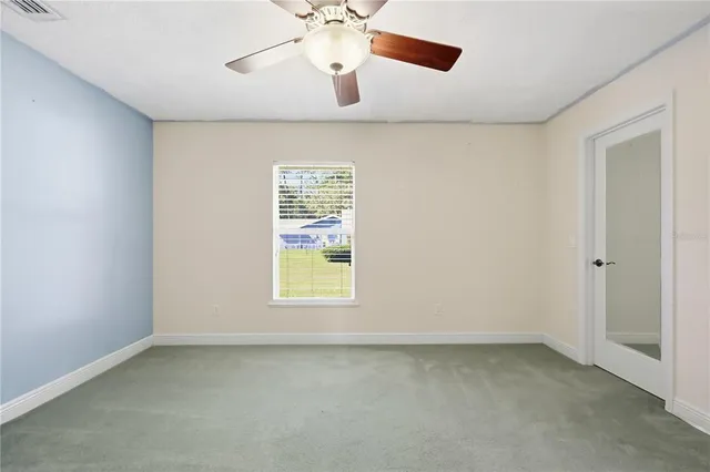 an empty room with a window and a ceiling fan