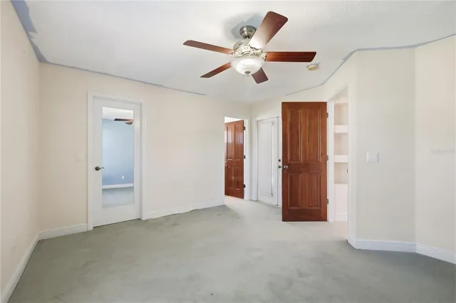 an empty room with closet and ceiling fan