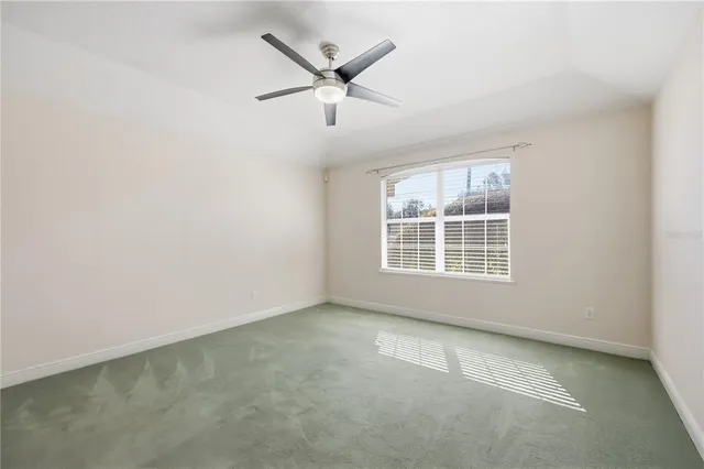 an empty room with windows and ceiling fan