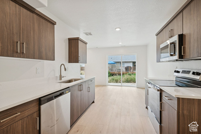 1615 North Angel Street, Unit E Layton, UT 84041 - Photo 16 of 42 Kitchen with appliances with stainless steel finishes, light stone counters, light wood-type flooring, modern cabinets, and dark brown cabinetry