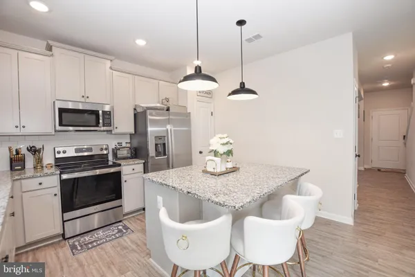 a kitchen with kitchen island granite countertop a sink a center island and stainless steel appliances