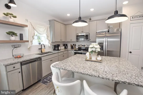 a kitchen with stainless steel appliances granite countertop a stove a sink a refrigerator a center island with a dining table and chairs