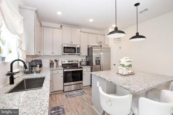 a living room with stainless steel appliances furniture and a wooden floor