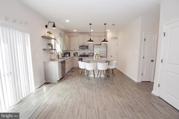a kitchen with kitchen island stainless steel appliances a dining table chairs sink and cabinets