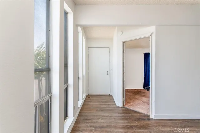 a view of a hallway with wooden floor and a bathroom