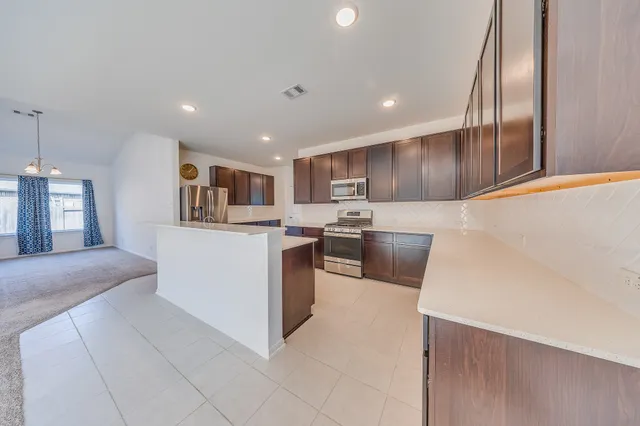 a large kitchen with stainless steel appliances stove a sink dishwasher and microwave oven