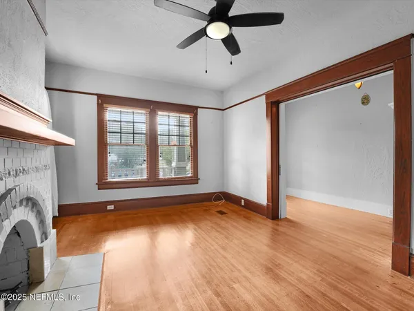 a view of an empty room with window and wooden floor