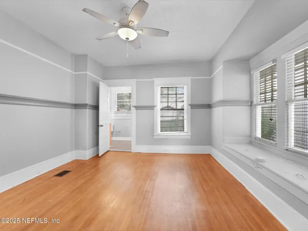 a view of empty room with wooden floor and fan