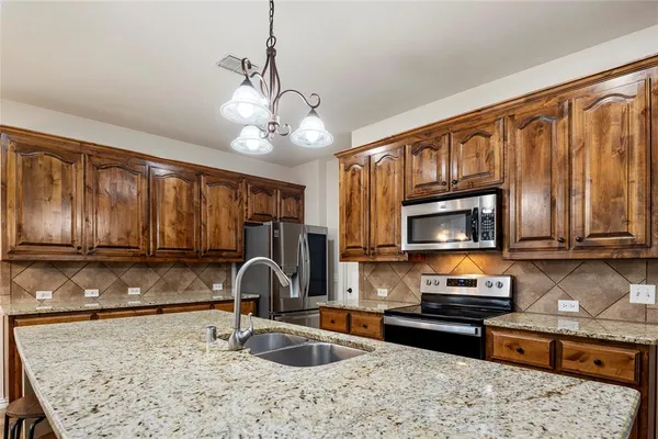 a large kitchen with kitchen island granite countertop a stove top oven a sink a dining table and chairs