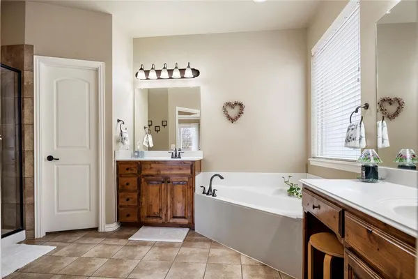 a spacious bathroom with a tub double sink and mirror