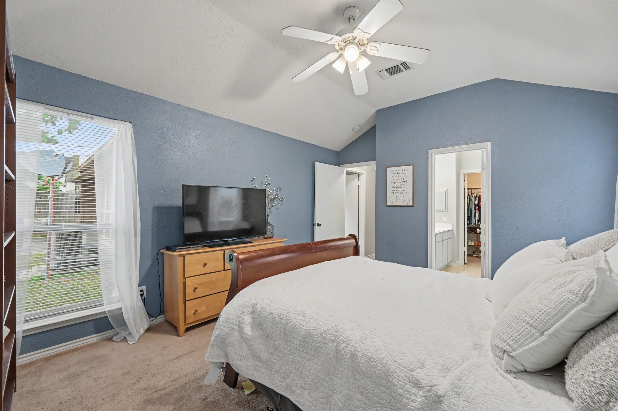 5226 Clarkston Lane Spring, TX 77379 - Photo 18 of 25 Spacious primary bedroom with vaulted ceilings, soothing blue walls, and an abundance of natural light. Includes ample closet space, and a convenient en-suite bathroom.