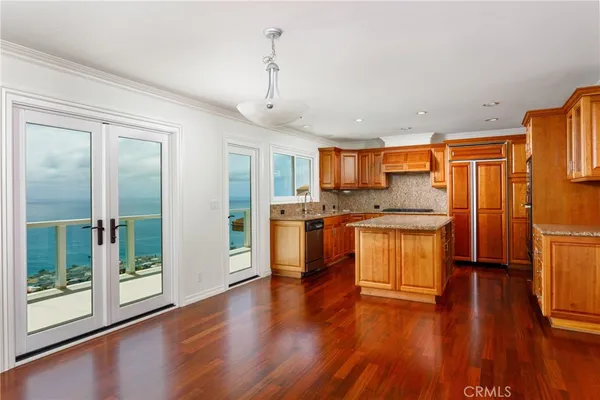 a kitchen with stainless steel appliances granite countertop a refrigerator a stove top oven and wooden floors