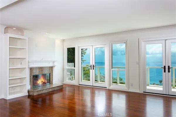 a view of an empty room with wooden floor fireplace and a window