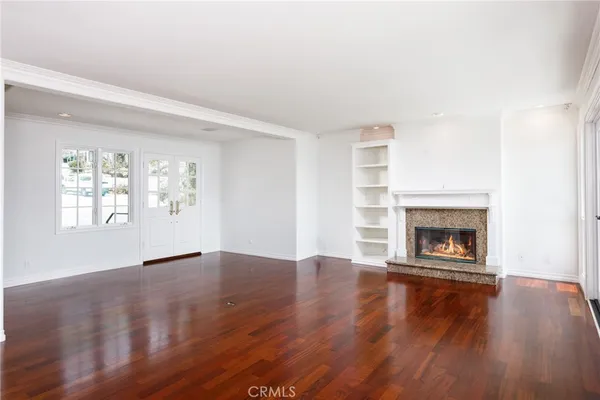 an empty room with wooden floor fireplace and windows