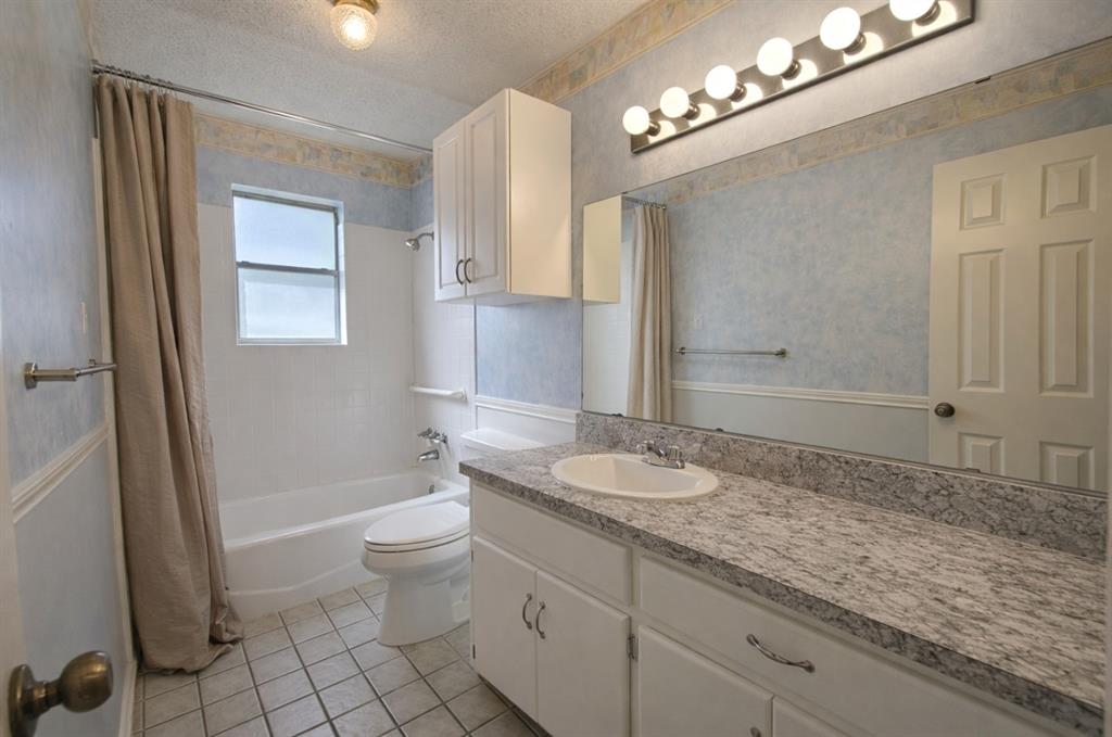 2302 Shiloh Street Denison, TX 75020 - Photo 11 of 16 a bathroom with a granite countertop sink a toilet a mirror and shower
