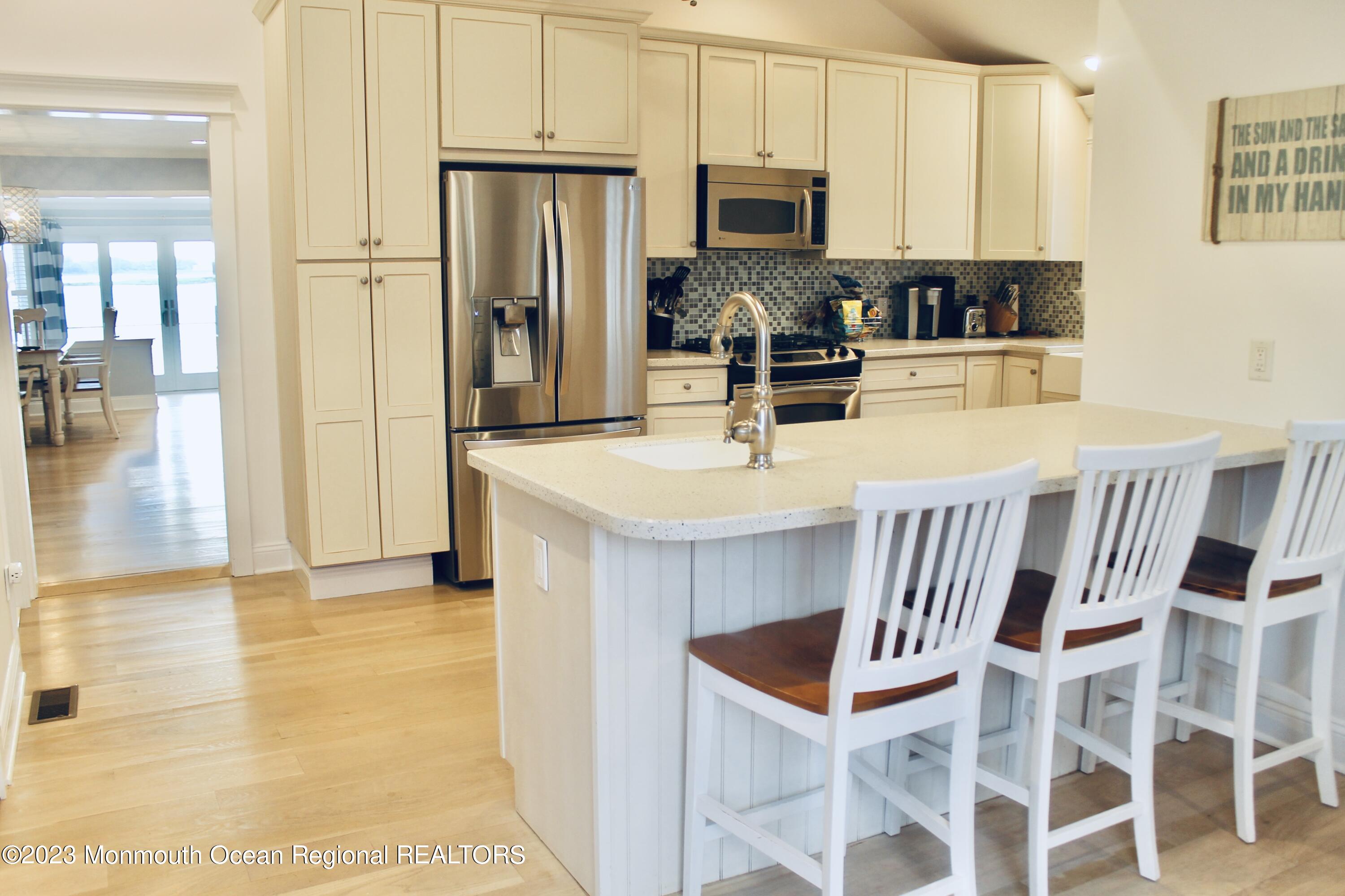 4 Riverview Place Sea Bright, NJ 07760 - Photo 4 of 17 a kitchen with stainless steel appliances kitchen island granite countertop a refrigerator a stove a sink and white cabinets with wooden floor