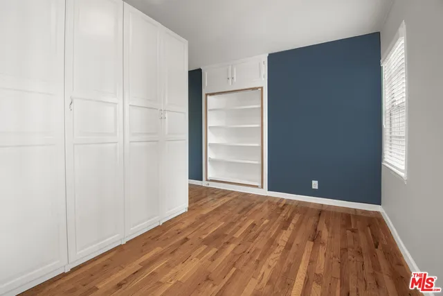 a view of an empty room with closet and wooden floor