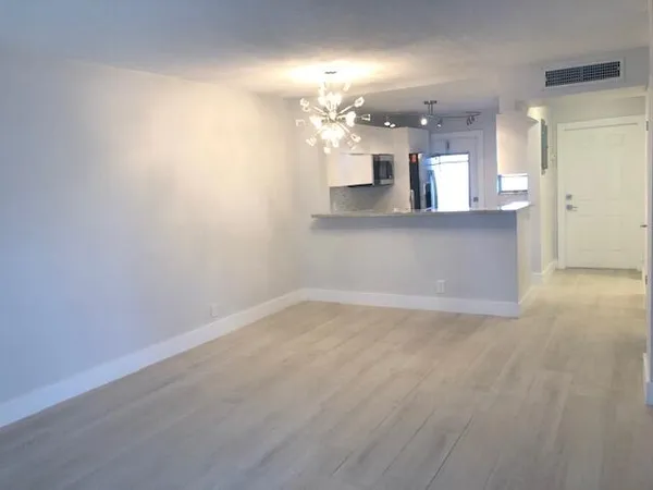 an empty room with kitchen and chandelier fan