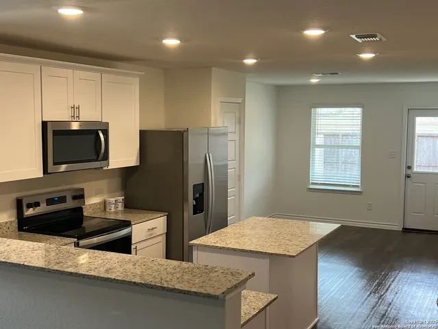 a kitchen with stainless steel appliances granite countertop a refrigerator a stove top oven a sink and dishwasher