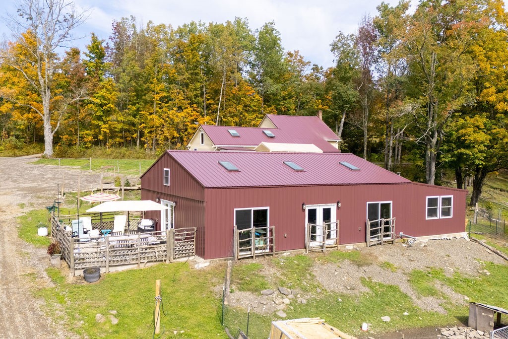 1668 Vandervort Hill Road Unadilla, NY 13849 - Photo 25 of 50 A metal outbuilding sits nestled against a dense backdrop of mature autumn trees.