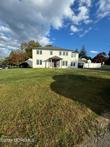 a view of a white house next to a yard with big trees