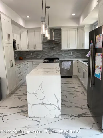 a large kitchen with granite countertop a stove a sink and a refrigerator