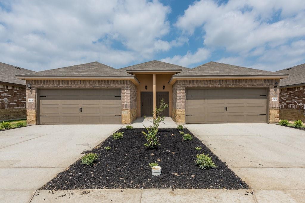 491 Jack Rabbit Lane, Unit A Buda, TX 78610 - Photo 22 of 22 A duplex property with a symmetrical facade, featuring dual garages and a well-maintained landscaping strip.