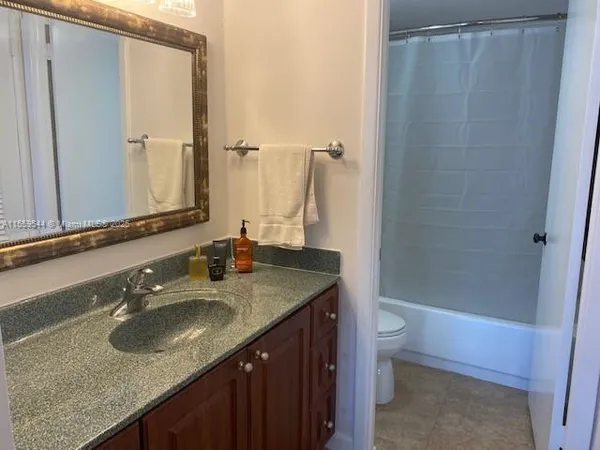 a bathroom with a granite countertop sink toilet and shower