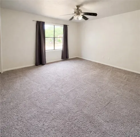 a view of a big room with windows and chandelier fan