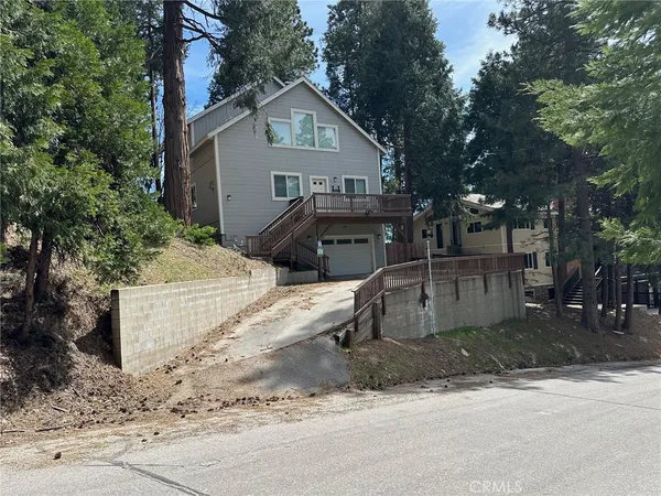 a view of a white house next to a road and trees