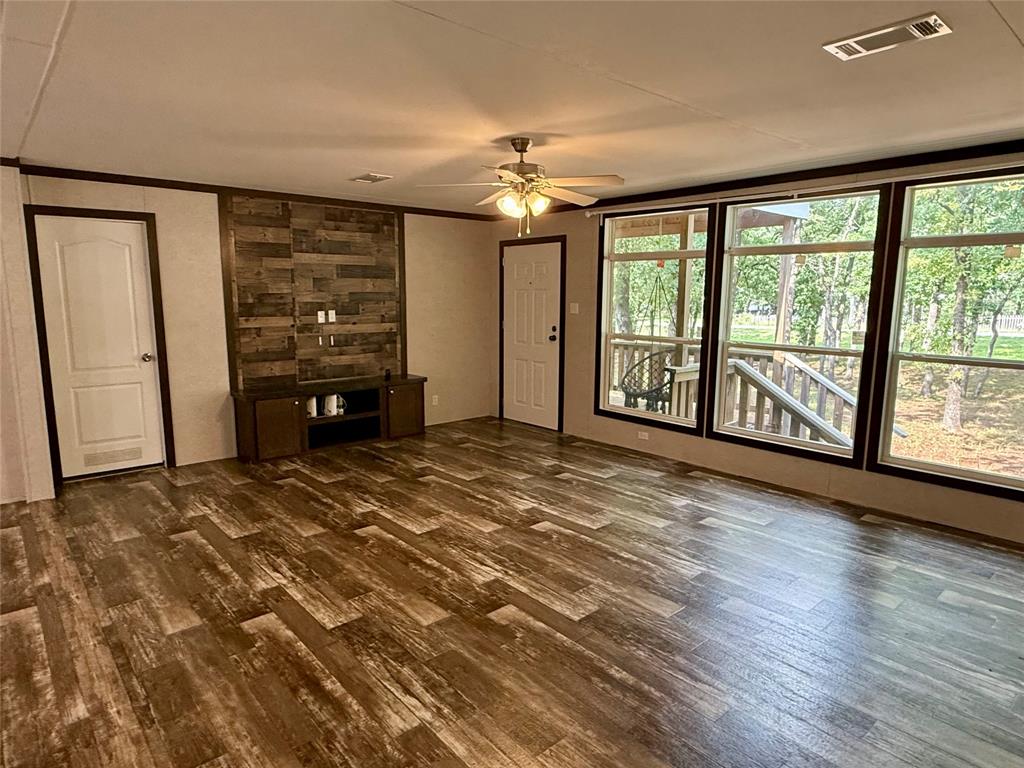 145 Adalida Lane Springtown, TX 76082 - Photo 6 of 29 Spacious interior featuring wood-finish flooring, a decorative accent wall with built-in cabinetry, and multiple large windows overlooking exterior nature
