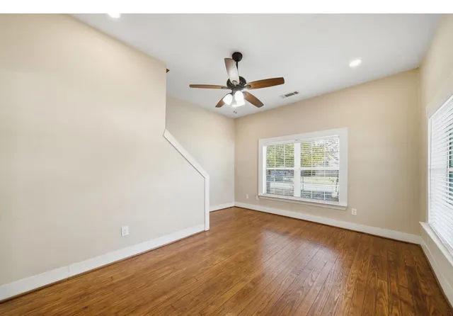 a view of empty room with wooden floor and fan