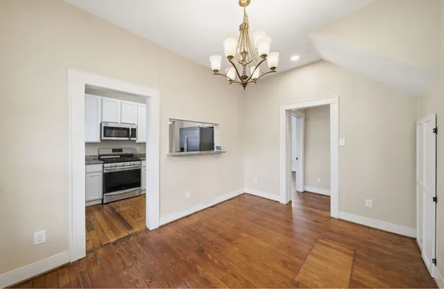 a view of an empty room with a window and wooden floor