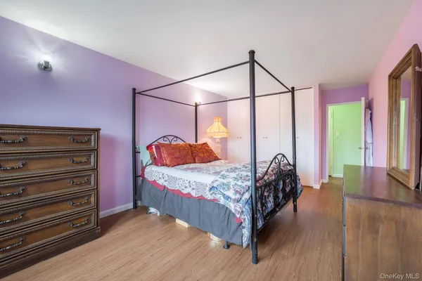 a bedroom with a bed a dresser with wooden floor
