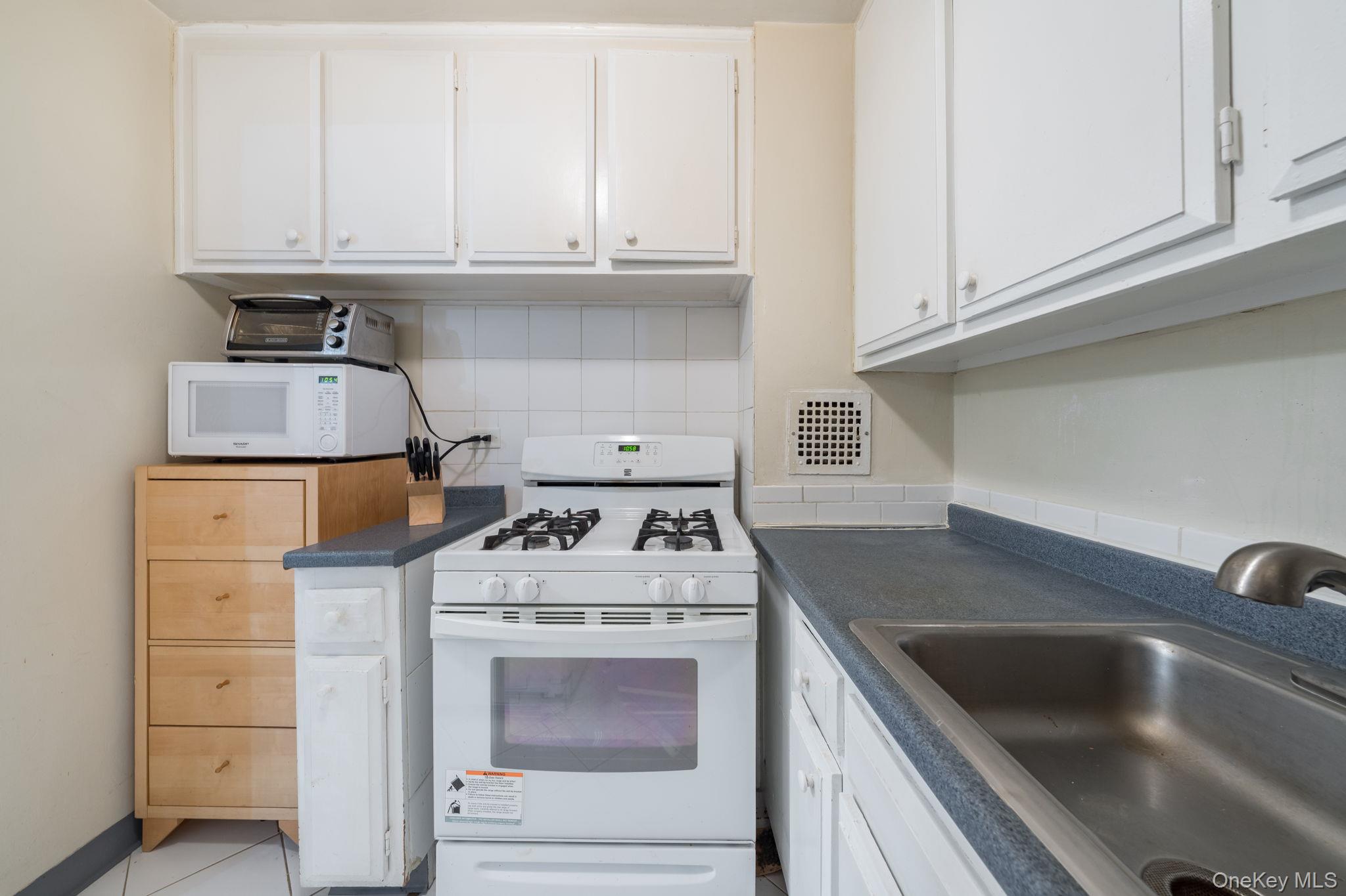 85-15 Main Street, Unit 3E Queens, NY 11435 - Photo 4 of 16 a kitchen with white cabinets and a stove top oven